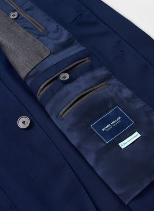Close-up of the inside of a navy Excursionist Flex Blazer by Peter Millar, highlighting buttons, inner pockets, and a fabric label with the brand name.
