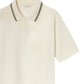 The Frame Light Pique Polo is an off-white, short-sleeve cotton shirt with black double stripes on the collar, a two-button placket, and the "FRAME" label inside—an everyday essential with timeless style.