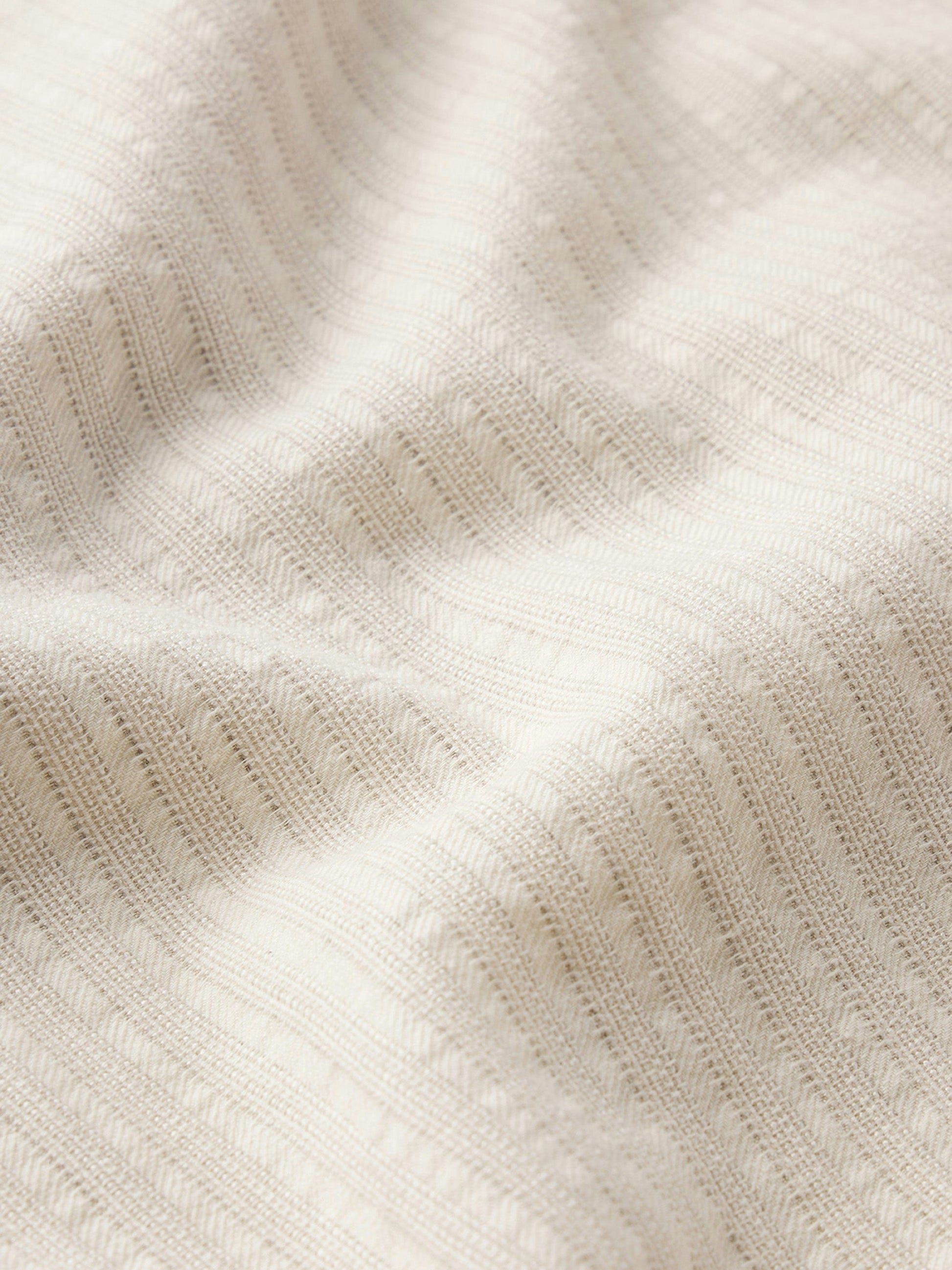 Close-up of the textured, cream jacquard cotton fabric used in Frame’s Jacquard Cotton Short-Sleeved Shirt—an airy, stylish choice for your summer wardrobe.
