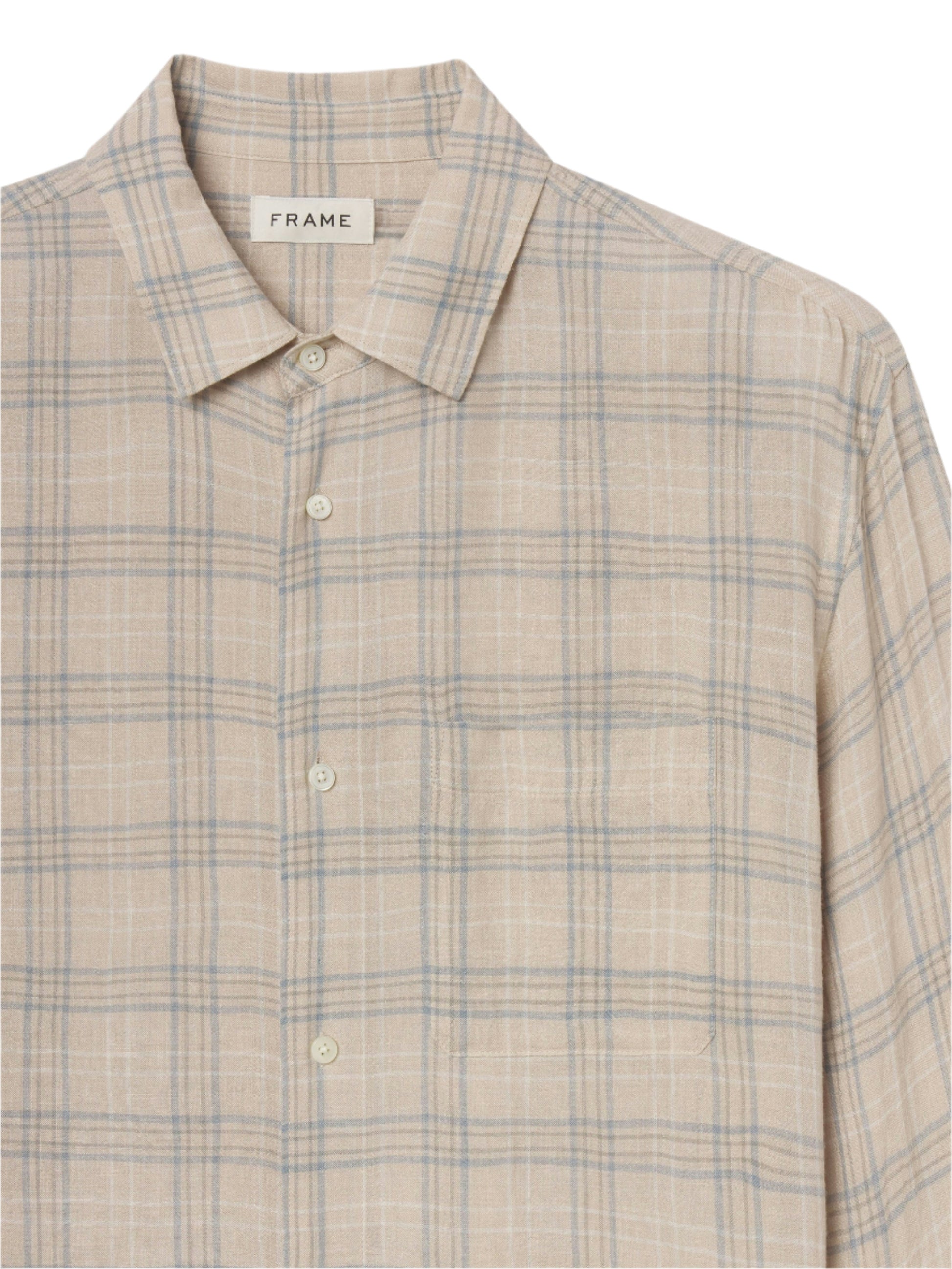 The Frame Plaid Shirt is a beige cotton-wool button-up with a collar and chest pocket, featuring light blue and white lines—an ideal everyday piece displayed against a plain background.