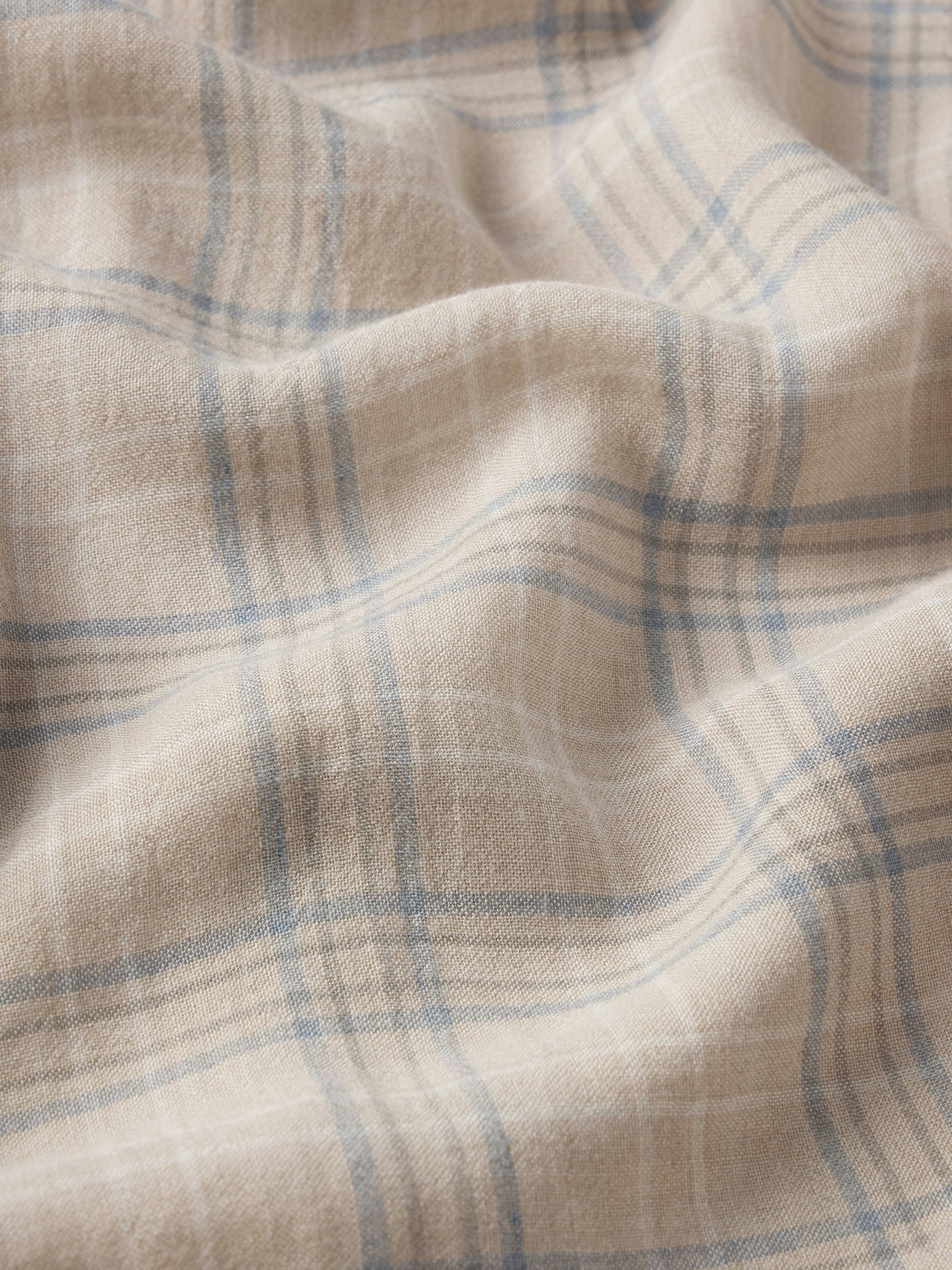 A close-up of Frame's Plaid Shirt shows its soft cotton-wool blend in blue and white with gentle folds, highlighting the comfortable texture—ideal for everyday wear.
