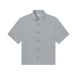 The Frame Lightweight Shirt is a light gray, short-sleeve button-up featuring a collar and a single chest pocket. Crafted from 100% cotton for a relaxed fit, this shirt is showcased lying flat against a white background.