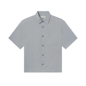 The Frame Lightweight Shirt is a light gray, short-sleeve button-up featuring a collar and a single chest pocket. Crafted from 100% cotton for a relaxed fit, this shirt is showcased lying flat against a white background.