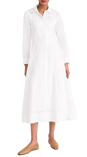 A person wearing a white Merlette Liberty Dress by Merlette New York with a collar and buttons down the front, paired with brown slip-on shoes, embodies sustainable fashion.