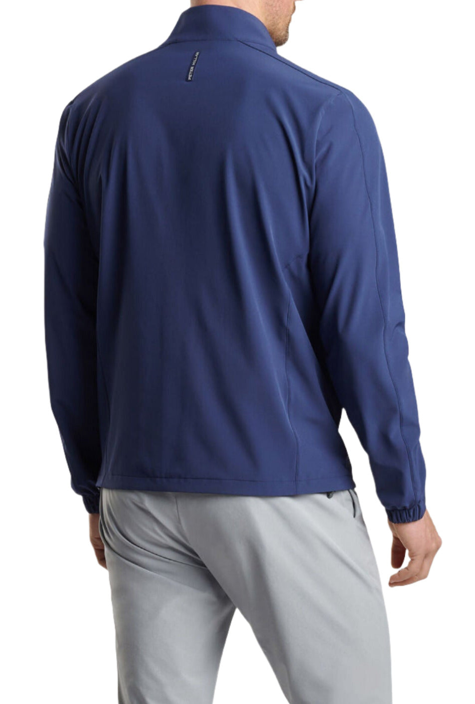 A person wearing a Peter Millar Contour Jacket, a men's tailored fit, blue long-sleeve jacket with four-way stretch, and light gray pants, seen from the back.