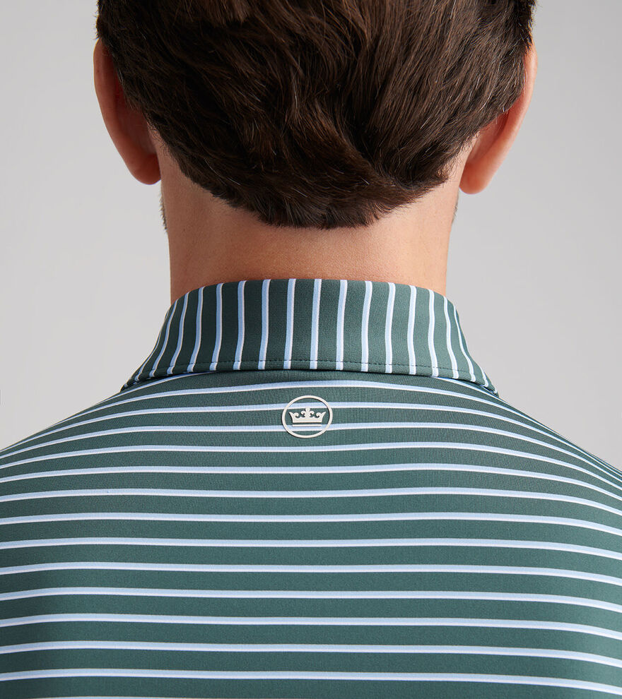 Back view of a person in the Peter Millar Dunnes Performance Jersey Polo, green and white striped, with four-way stretch and a small circular crown logo below the collar.