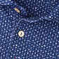 Close-up of the Peter Millar Sidecar Performance Jersey Polo in blue, featuring a small white cocktail glass pattern, gold-colored buttons, and four-way stretch fabric for maximum comfort.