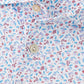 Close-up of the Peter Millar Orange Crush Performance Jersey Polo, featuring a vibrant science-themed pattern with microscopes, atoms, flasks, four-way stretch fabric, and cream-colored buttons.