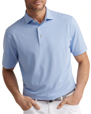 A man wears a light blue and white striped Lenway Performance Jersey Polo by Peter Millar, featuring UPF 50+ and four-way stretch, paired with white pants and his hands in his pockets.