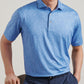 A man wearing the Peter Millar Champagne and Caviar Performance Jersey Polo with four-way stretch and a subtle white pattern, paired with navy blue pants, sits on a chair against a plain background.