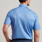 A man with short brown hair wears a light blue Champagne and Caviar Performance Jersey Polo by Peter Millar and dark blue pants, shown from the back against a neutral background.
