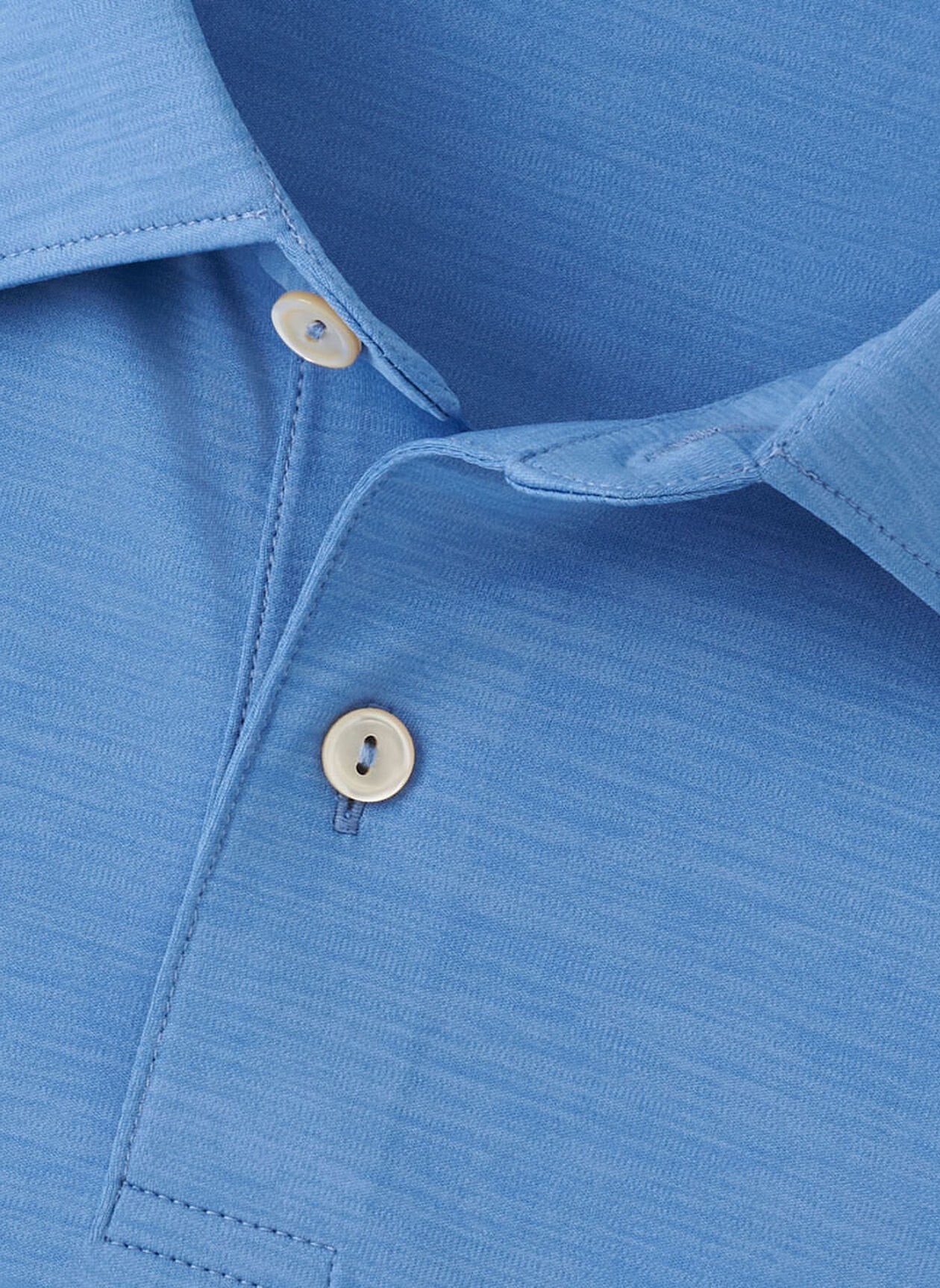 Close-up of the Peter Millar Featherweight Mélange Performance Polo in light blue, highlighting the top portion with two white buttons and its textured performance fabric pattern.