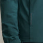 Close-up of a person's arm wearing the Peter Millar Dunes Half-Zip in teal, showcasing four-way stretch double-weave fabric, a visible logo, side pocket, and a velcro strap at the cuff.