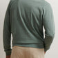 A man is shown from the back wearing the Peter Millar Crown Comfort Knit Crew in light green and beige pants against a plain background.