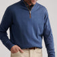 Man wearing the Peter Millar Autumn Crest Suede Trim Quarter-Zip in blue over a collared shirt and beige pants, smiling while looking down with one hand in his pocket.