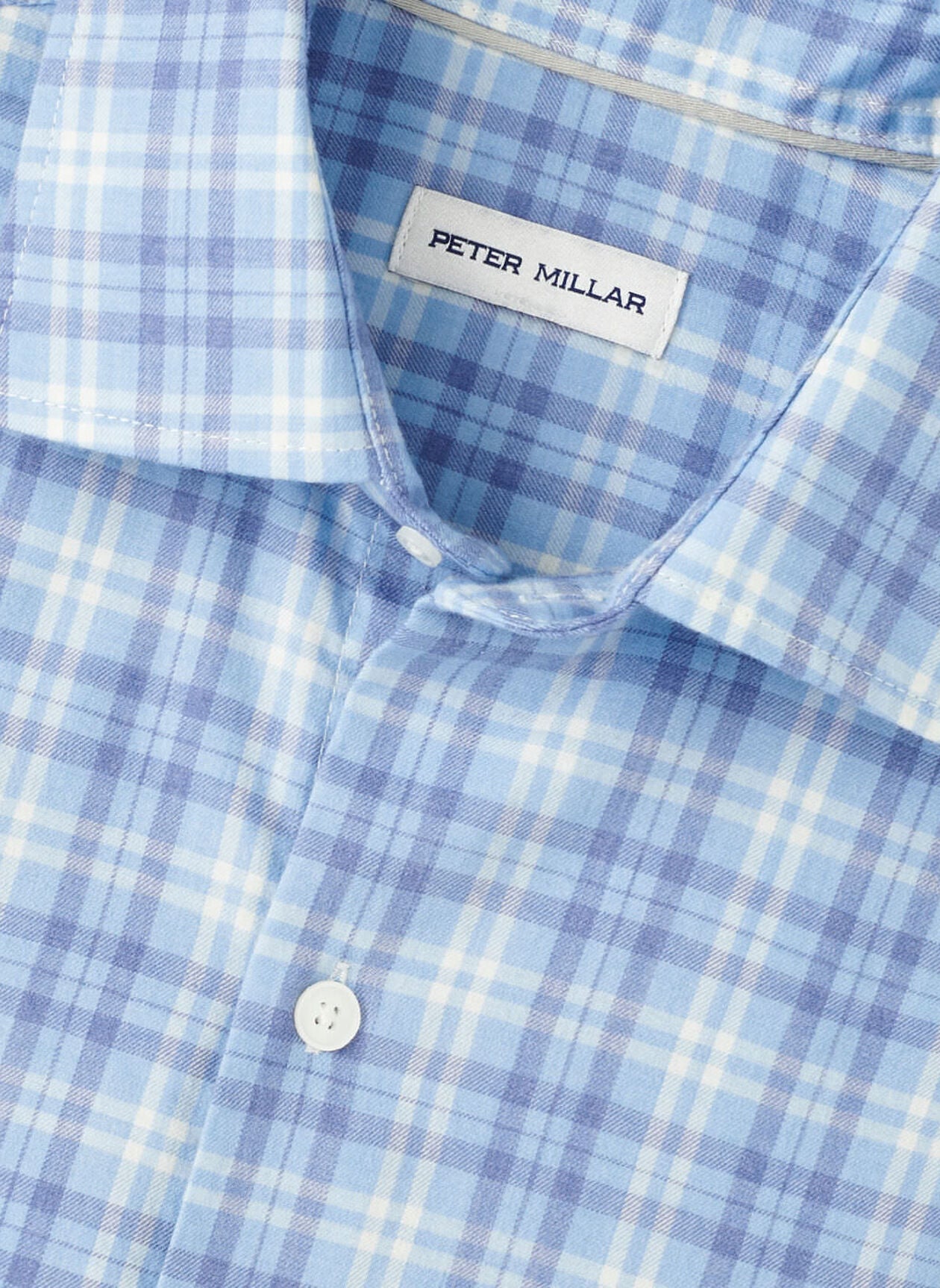 Close-up of the Peter Millar Bar Harbor Performance Flannel Sport Shirt in light blue and white plaid, featuring a button-up front and soft performance fibers, with the "Peter Millar" label sewn inside the collar.