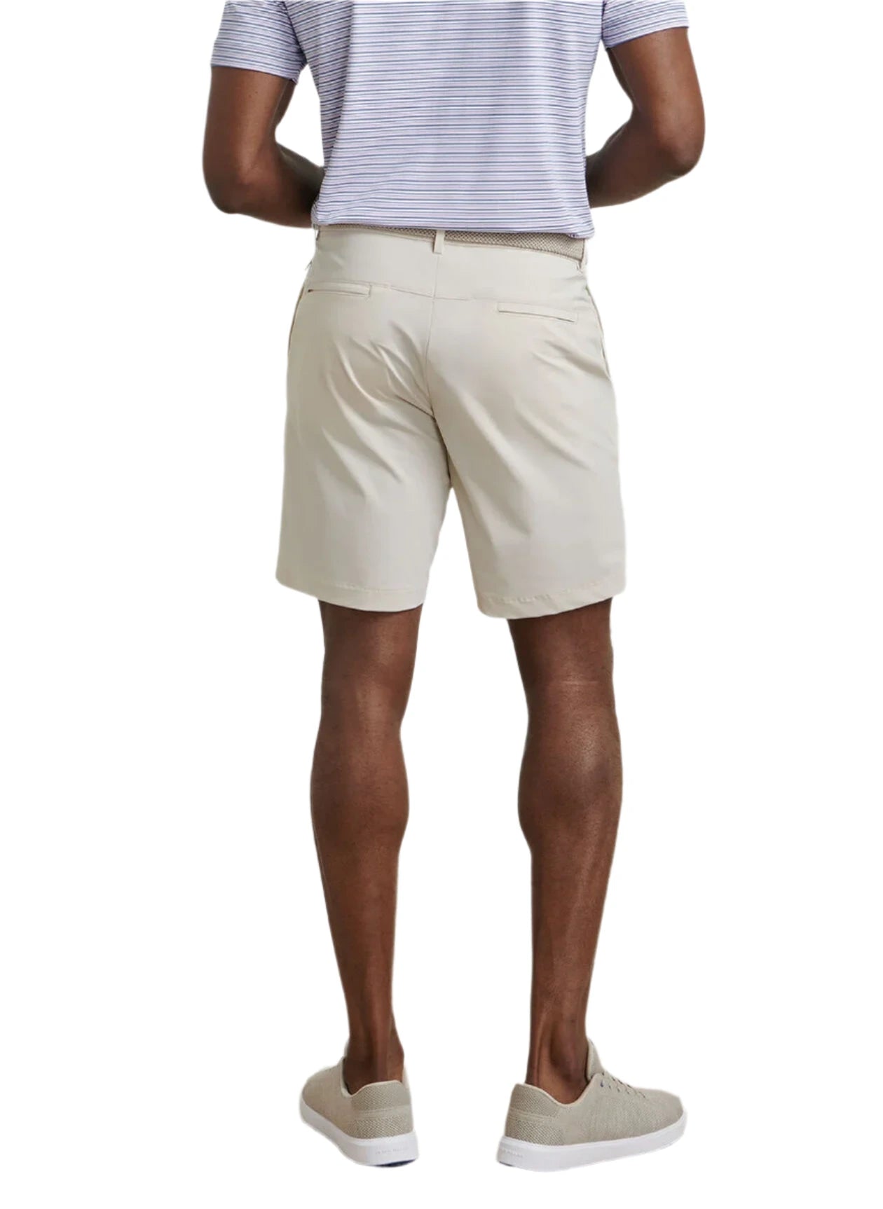A man faces away, wearing a light grey striped polo, Peter Millar Bingham Performance Short in beige, and light grey sneakers against a white background.