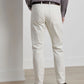 A person wearing a checkered shirt, white Peter Millar Fairfield Garment Dyed Denim pants, and brown shoes stands with their back to the camera, facing a wall.