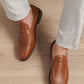 A person in light-colored pants wears Peter Millar's Madison Penny Loafers, crafted from tumbled calf leather, standing on a light wood floor and displaying modern versatility.