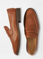 The Peter Millar Madison Penny Loafer is a pair of brown modern shoes crafted from tumbled calf leather with stitching details and flat soles, shown from top and side views.