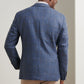 A man wearing the Peter Millar Delrose Plaid Soft Jacket and beige pants stands facing away from the camera against a light-colored wall.