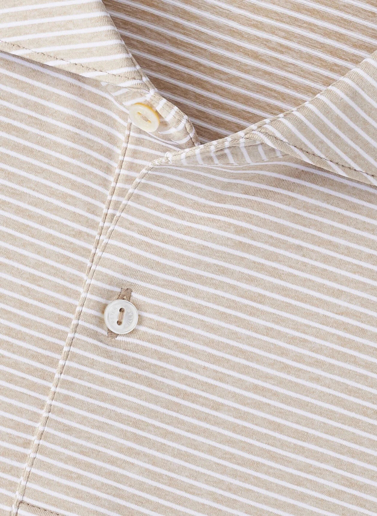 Close-up of the Peter Millar Ballad Performance Jersey Polo, a beige and white striped collared shirt with two white buttons, crafted from soft jersey fabric for four-way stretch comfort.