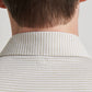 Close-up of the back of a person’s neck and shoulders wearing the Peter Millar Ballad Performance Jersey Polo in light beige and white stripes, featuring a small round logo at the collar and UPF 50+ sun protection.