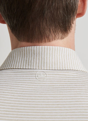 Close-up of the back of a person’s neck and shoulders wearing the Peter Millar Ballad Performance Jersey Polo in light beige and white stripes, featuring a small round logo at the collar and UPF 50+ sun protection.