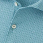 Close-up of the Peter Millar Corinth Performance Jersey Polo, a light blue shirt with a small leaf-like pattern, two white buttons, and four-way stretch for comfort.