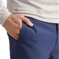 A person wearing a Peter Millar Stealth Performance Quarter-Zip and blue pants stands with one hand in their pocket.