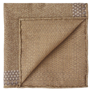 The Wells Pocket Square by Peter Millar features elegant brown Italian wool, folded to highlight its subtle herringbone pattern and small geometric corner designs.