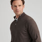 A man wearing the Peter Millar Excursionist Flex Quarter-Zip Sweater in brown over a white collared shirt looks to the side against a plain light background.