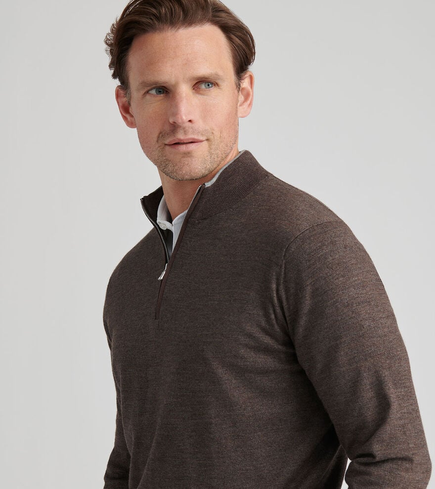 A man wearing the Peter Millar Excursionist Flex Quarter-Zip Sweater in brown over a white collared shirt looks to the side against a plain light background.