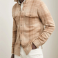 A man in the Peter Millar Gordon Plaid Sweater Shirt Jacket—beige and tan plaid Merino wool with chest pockets—pairs it with white pants for a minimal, versatile style, standing with one hand in his pocket.