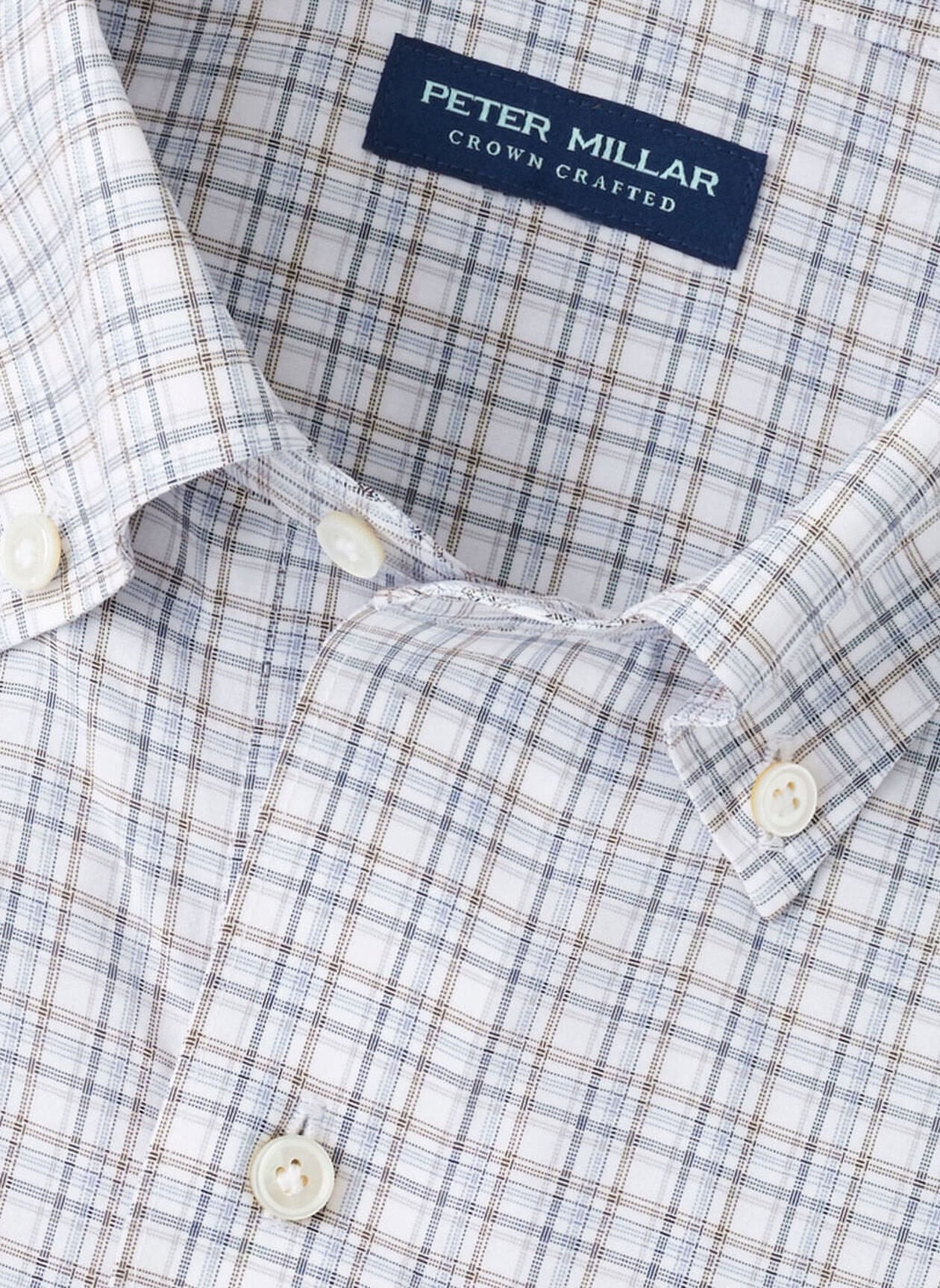 Close-up of the Peter Millar Carter Performance Poplin Sport Shirt, showcasing a blue and brown plaid pattern, white buttons, and four-way stretch for all-day comfort.