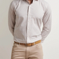 A man in a Peter Millar Orvieto Cotton Sport Shirt, paired with beige pants and a tan belt, stands with his hands behind his back.