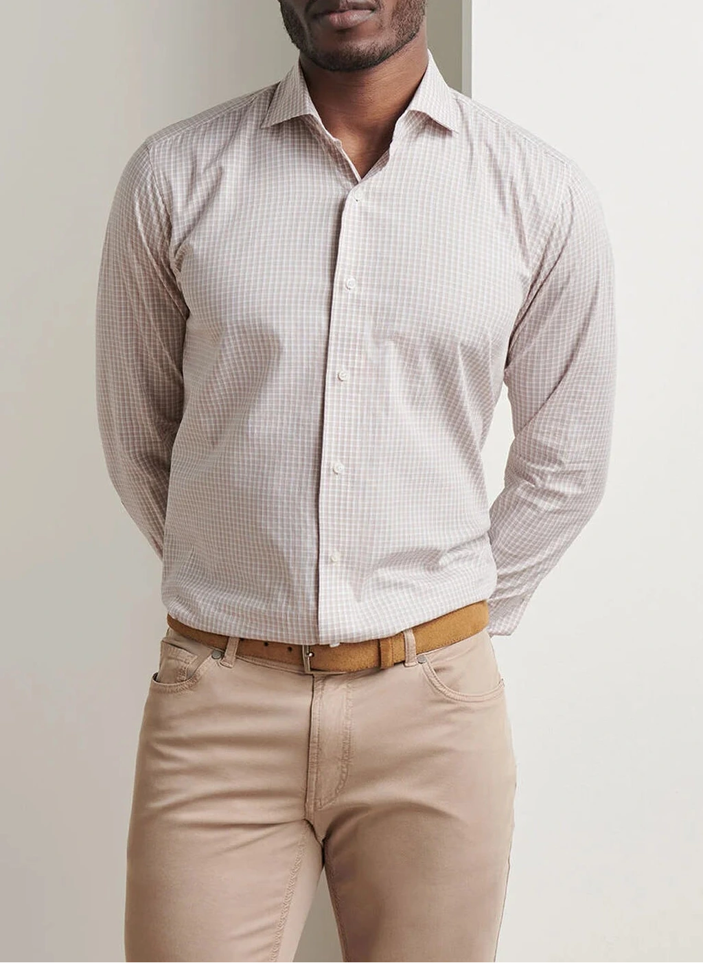 A man in a Peter Millar Orvieto Cotton Sport Shirt, paired with beige pants and a tan belt, stands with his hands behind his back.