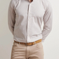 A man stands against a white background wearing a Peter Millar Torino Cotton Sport Shirt in a light checkered pattern, paired with beige pants and a tan belt.