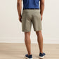 Back view of a person wearing Crown Comfort Short 8″ inseam khaki shorts, a blue polo shirt, and navy sneakers, showcasing a clean, plain weave fabric.