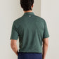 Back view of a person wearing a green and white striped Peter Millar Oaks Performance Jersey Polo with a small circular logo at the base of the collar.