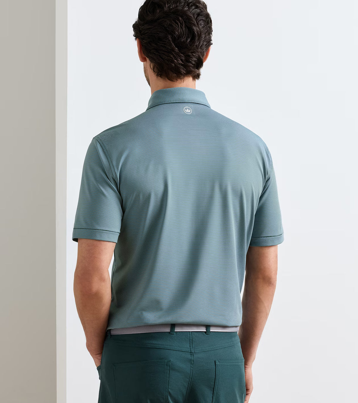 Back view of a person wearing a teal, fine-striped Jubilee Performance Jersey Polo with a small logo on the back of the neck, tucked into dark green trousers.