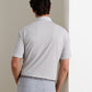 A man stands with his back to the camera, wearing the Peter Millar ETC Stripe Performance Jersey Polo in light gray along with matching pants against a neutral background, embodying effortless Summer Comfort.