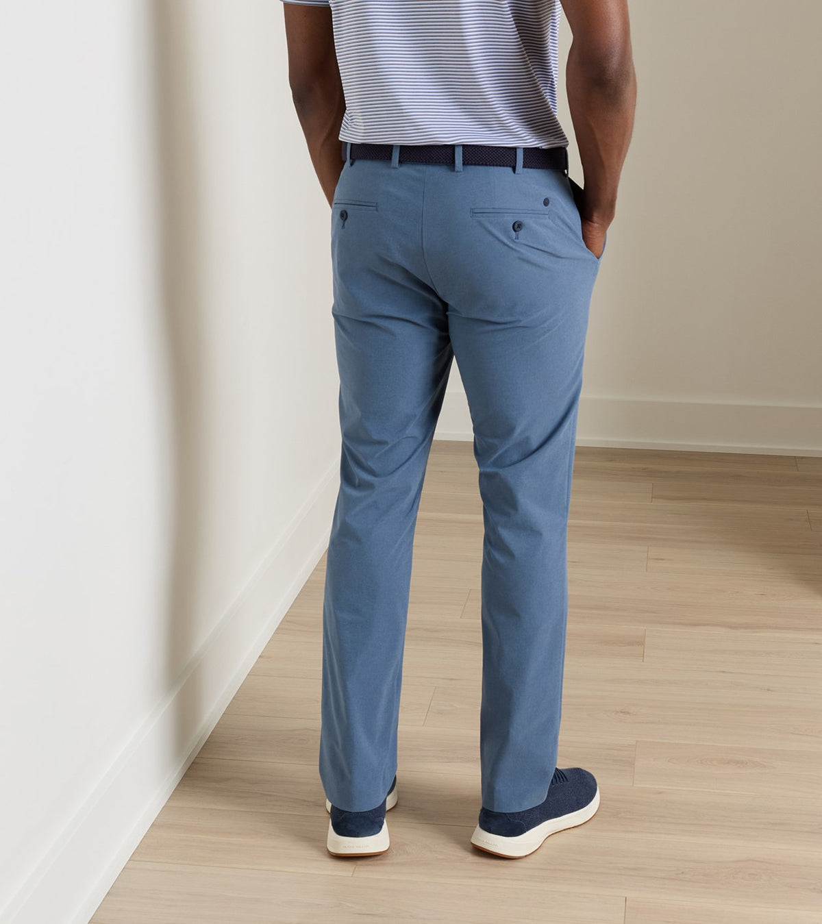 Back view of a person wearing blue Peter Millar Surge Performance Trouser, a striped shirt, and blue sneakers.