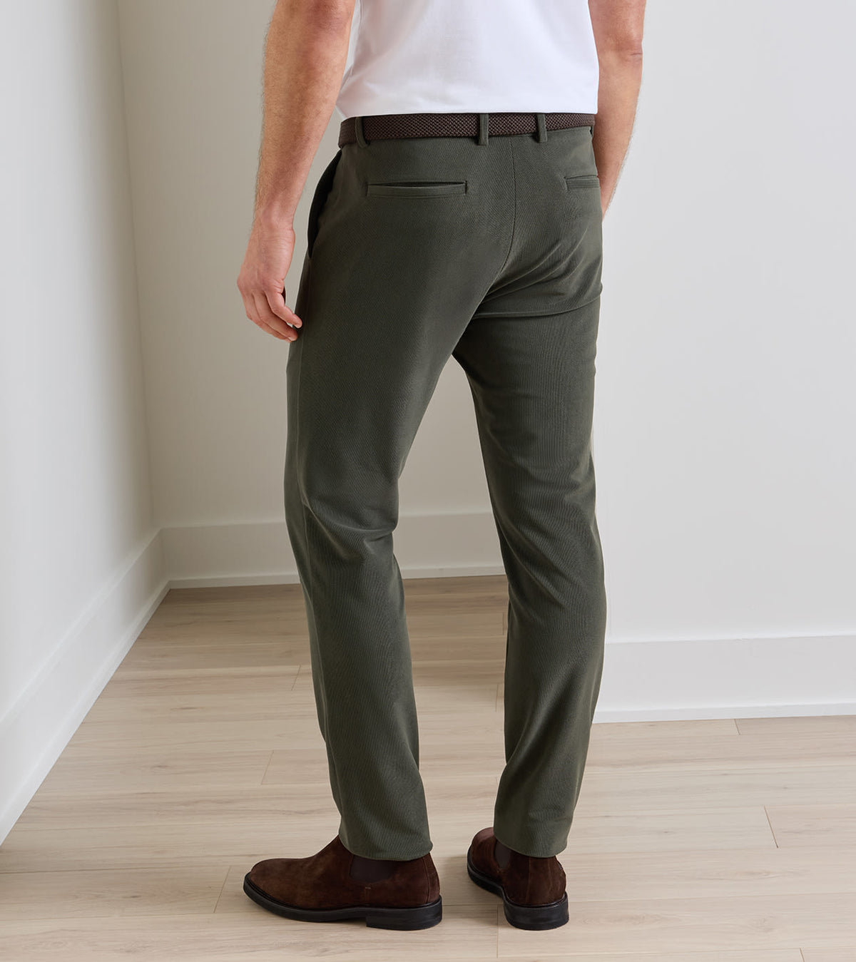 Rear view of a person wearing olive green Bingham Corduroy Performance Trouser, a white shirt, and dark brown suede boots.
