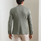 Back view of a man wearing a textured sage green Peter Millar Barclay Knit Soft Jacket and beige trousers.