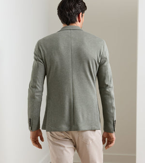 Back view of a man wearing a textured sage green Peter Millar Barclay Knit Soft Jacket and beige trousers.