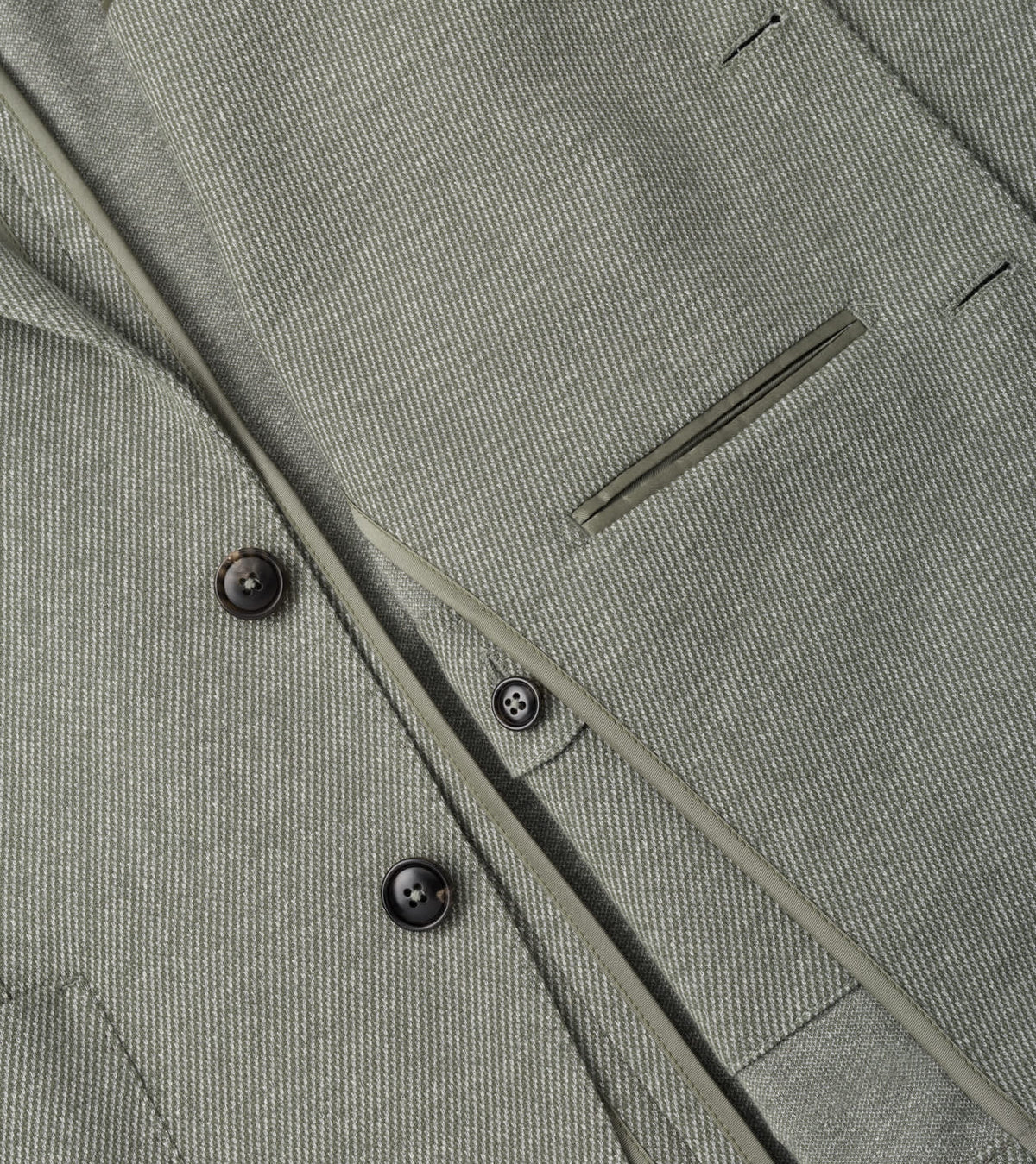 Close-up of a sage green Peter Millar Barclay Knit Soft Jacket featuring a button-front closure and a chest welt pocket.