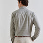 Back view of a man wearing an olive and white Peter Millar Excursionist Flex Gingham Sport Shirt tucked into light-colored trousers with a brown belt.