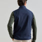 View from behind of a person wearing a navy blue water-resistant Peter Millar Ryder Reversible Vest over an olive green long-sleeved shirt and light-colored trousers.