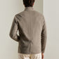 Back view of a man wearing a tan Peter Millar Crown Flex Merino blazer with a stand collar.